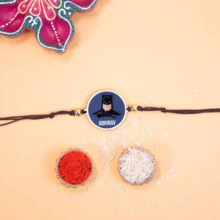 Personalized Handmade Batman Wooden Kids Rakhi With Roli Chawal - Flat lay with rakhi and ritual items