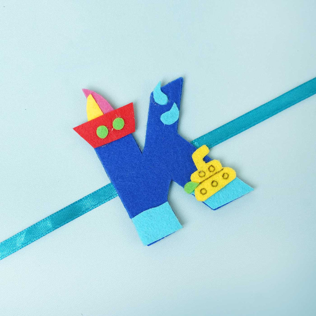 Personalised Handmade Boat Felt Rakhi With Chocolates Roli Chawal - Close-up of Blue K Rakhi