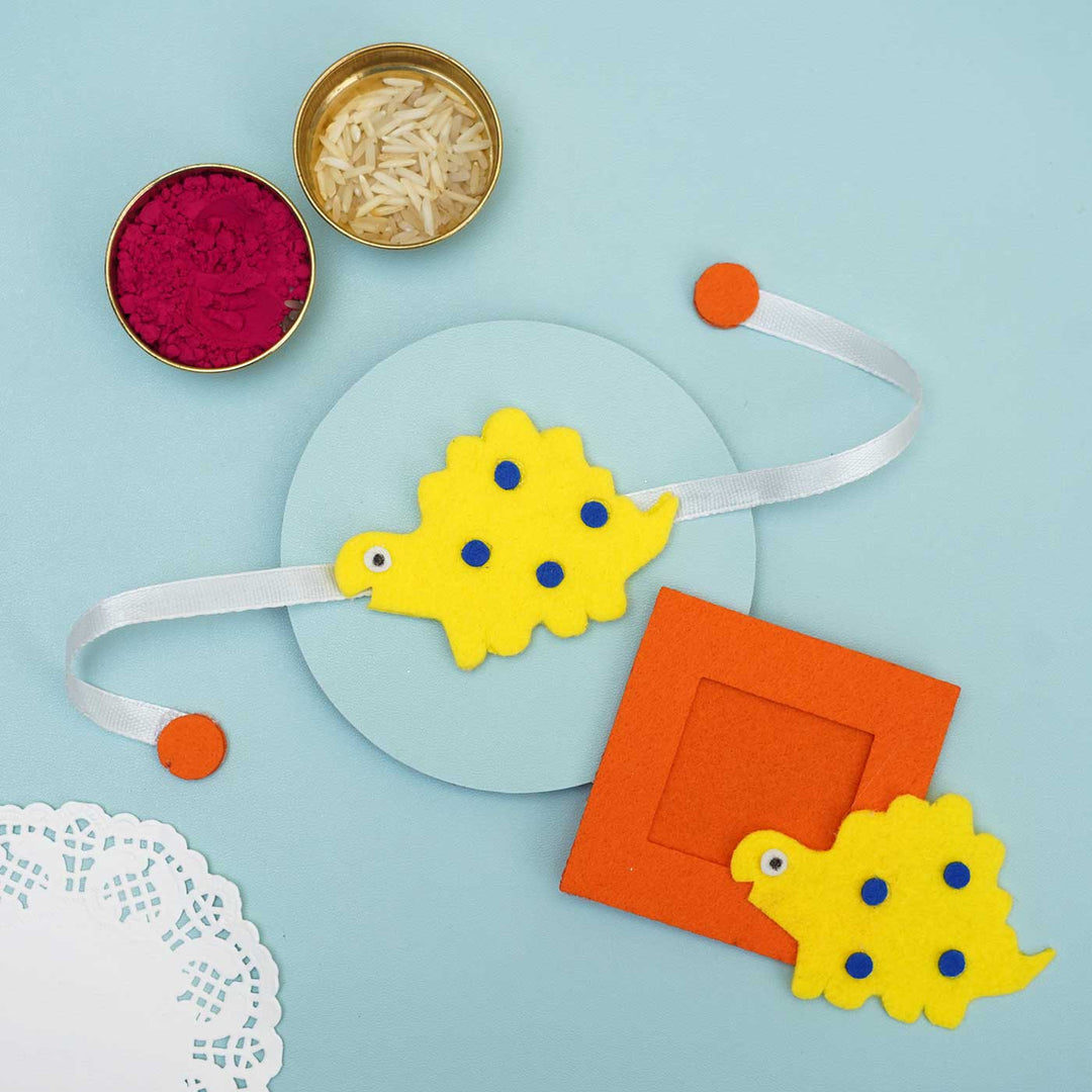 Handmade Blue Dinosaur Felt Rakhi Photoframe Magnet With Chocolates Roli Chawal - Decorative Rakhi Wristband on Display