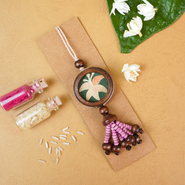 Handmade Eco Friendly Lily Pressed Flower Lumba Rakhi For Bhabhi With Roli Chawal - Flat lay with natural elements