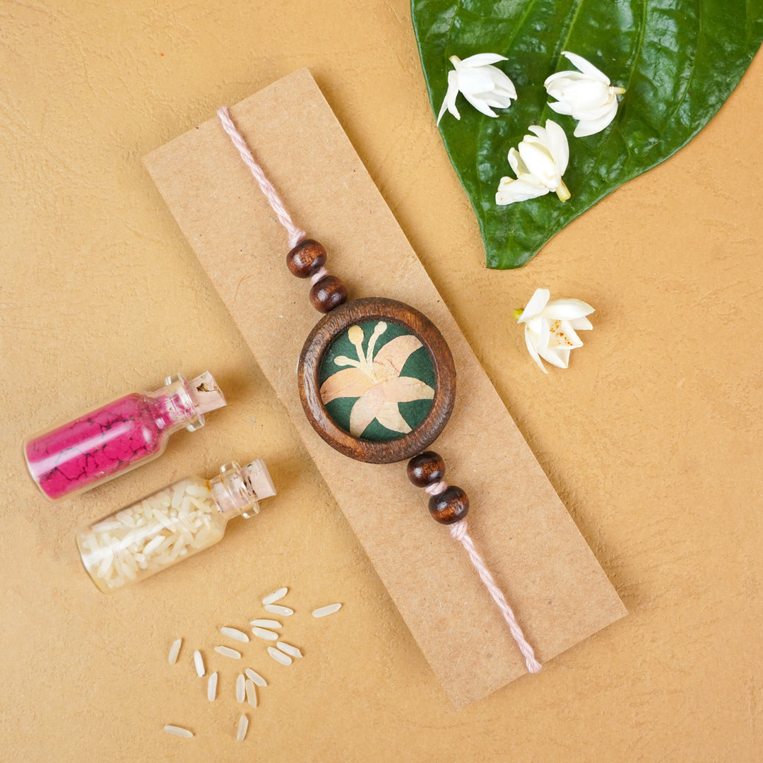 Handmade Eco Friendly Lily Pressed Flower Rakhi With Roli Chawal - Flat lay with decorative elements
