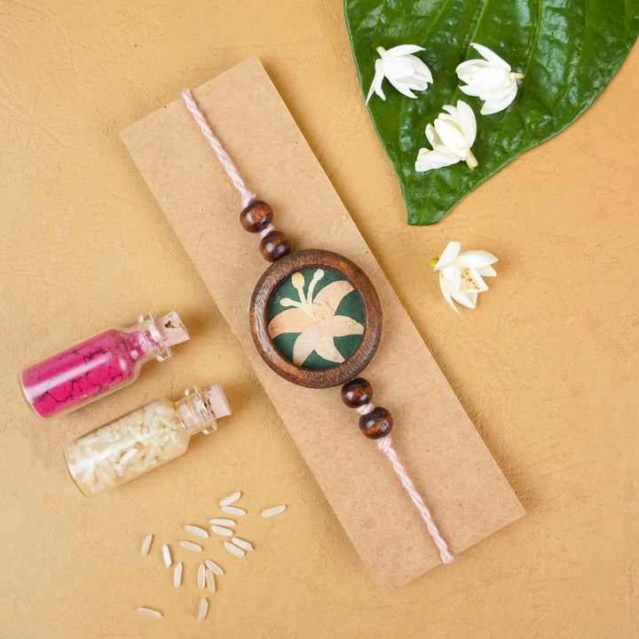 Handmade Eco Friendly Lily Pressed Flower Rakhi With Roli Chawal - Flat lay with decorative elements