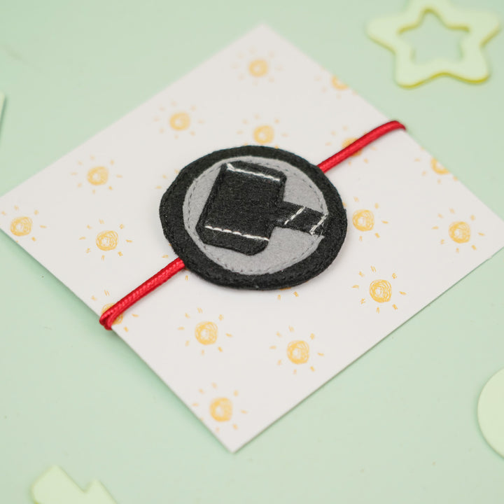 Handmade Thor Hammer Theme Felt Kids Rakhi For Brother - Bracelet on Patterned Card Close-up
