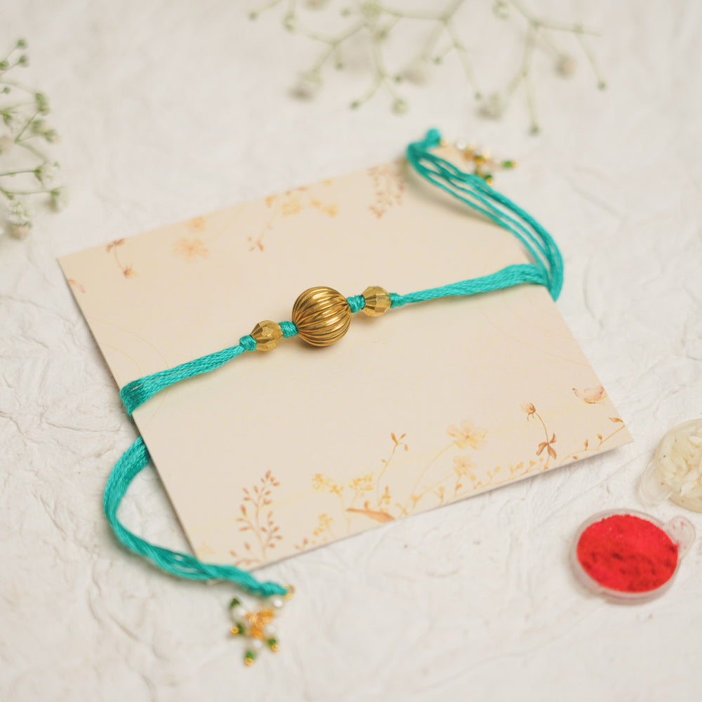 Handmade Swarn Pearl And Ghungroo Rakhi With Roli Chawal - Front view on decorative card