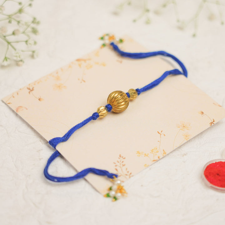 Handmade Swarn Pearl And Ghungroo Rakhi With Roli Chawal - Front view flat on card