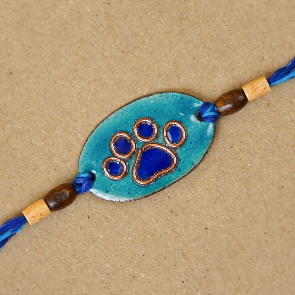 Handmade Pawfect Copper Enamel Rakhi With Chocolates And Roli Chawal - Close-up of Blue Paw Charm