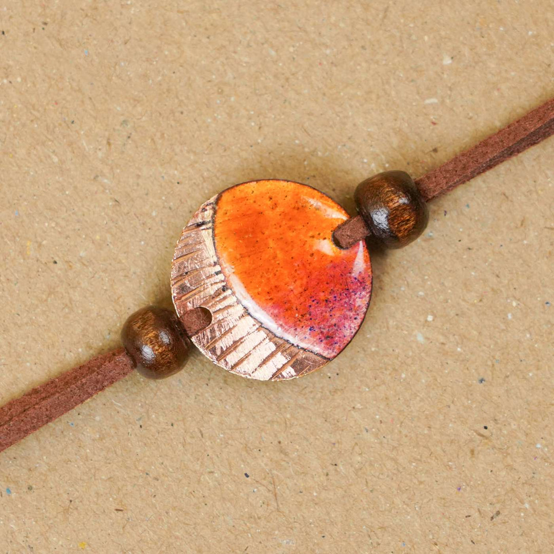 Handmade Ambar Textured Yellow Copper Enamel Rakhi With Chocolates & Roli Chawal