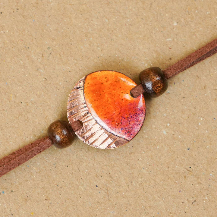 Handmade Ambar Textured Yellow Copper Enamel Rakhi With Chocolates & Roli Chawal
