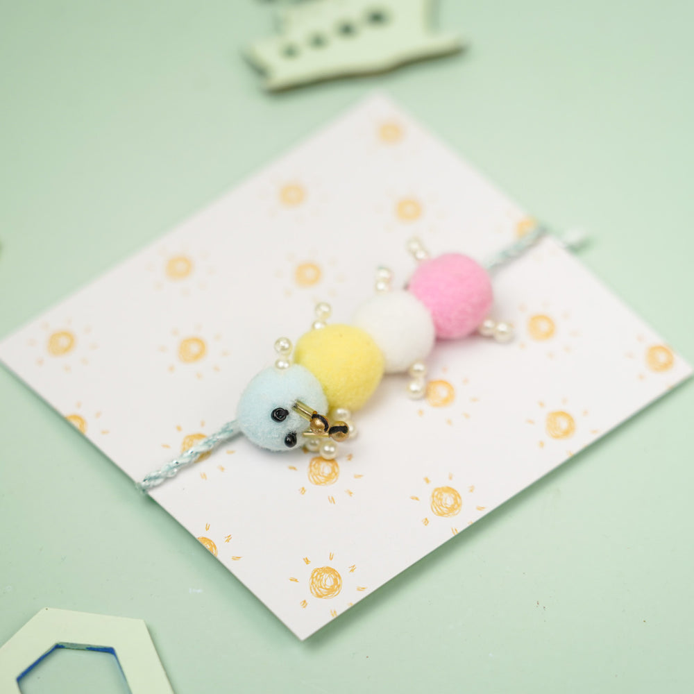 Handmade Caterpillar Pom Pom Design Kids Rakhi With Roli Chawal - Angled Close-up View