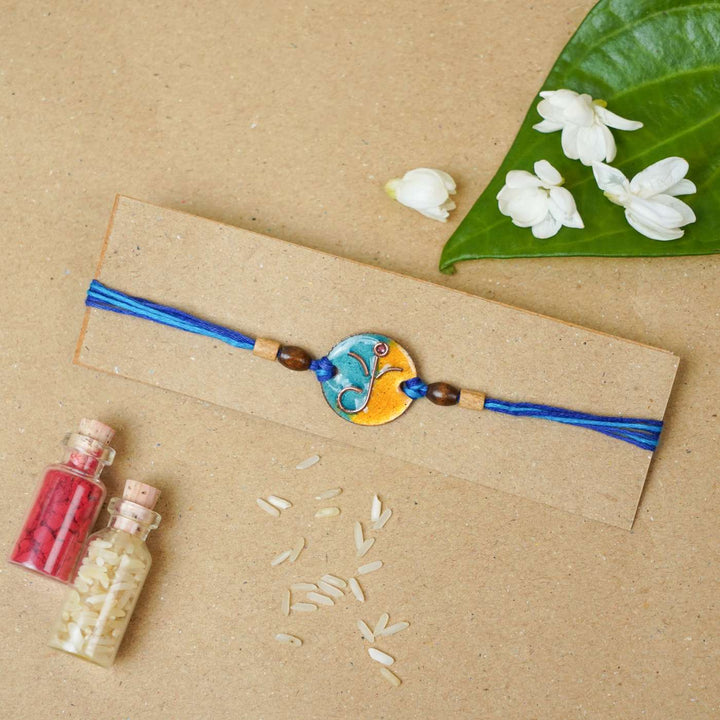 Handmade Round Ganesh Copper Enamel Rakhi With Chocolates & Roli Chawal