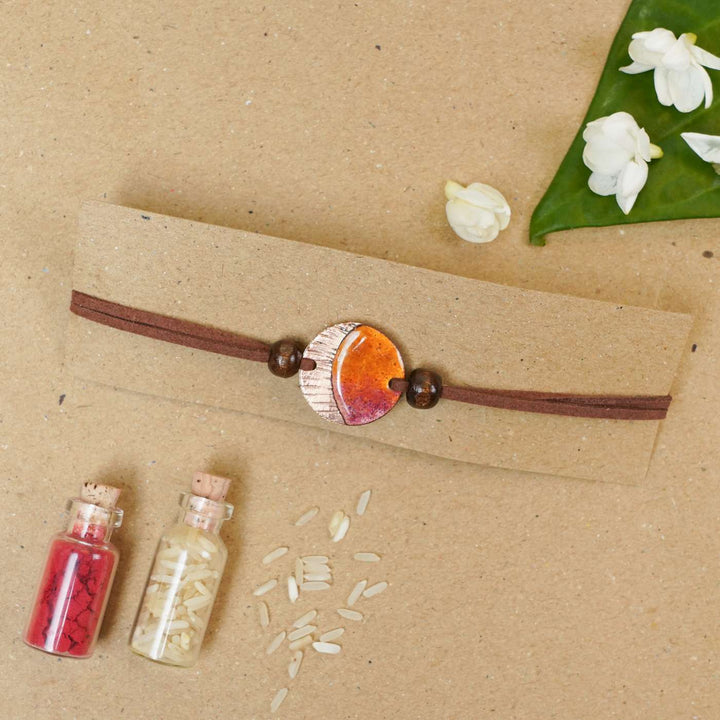 Handmade Ambar Textured Yellow Copper Enamel Rakhi With Chocolates & Roli Chawal