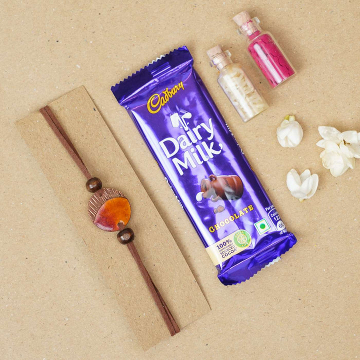 Handmade Ambar Textured Yellow Copper Enamel Rakhi With Chocolates & Roli Chawal