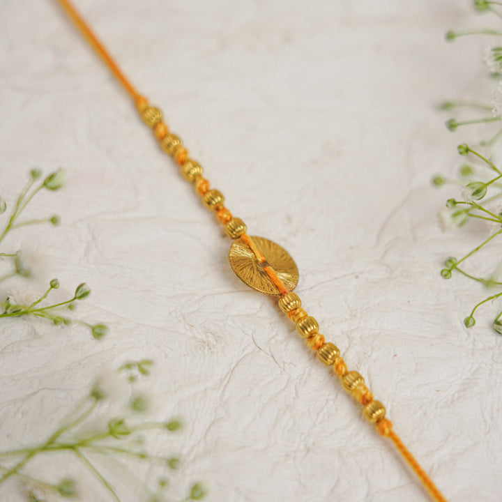 Handmade Swarn Sutra Ghungroo Bhaiya Bhabhi Rakhi With Roli Chawal - Close-up of Circle Detail Orange