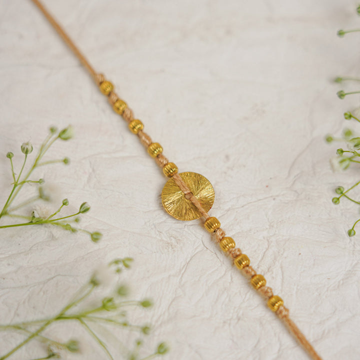 Handmade Swarn Sutra Ghungroo Bhaiya Bhabhi Rakhi With Roli Chawal - Close-up of Circle Detail Beige