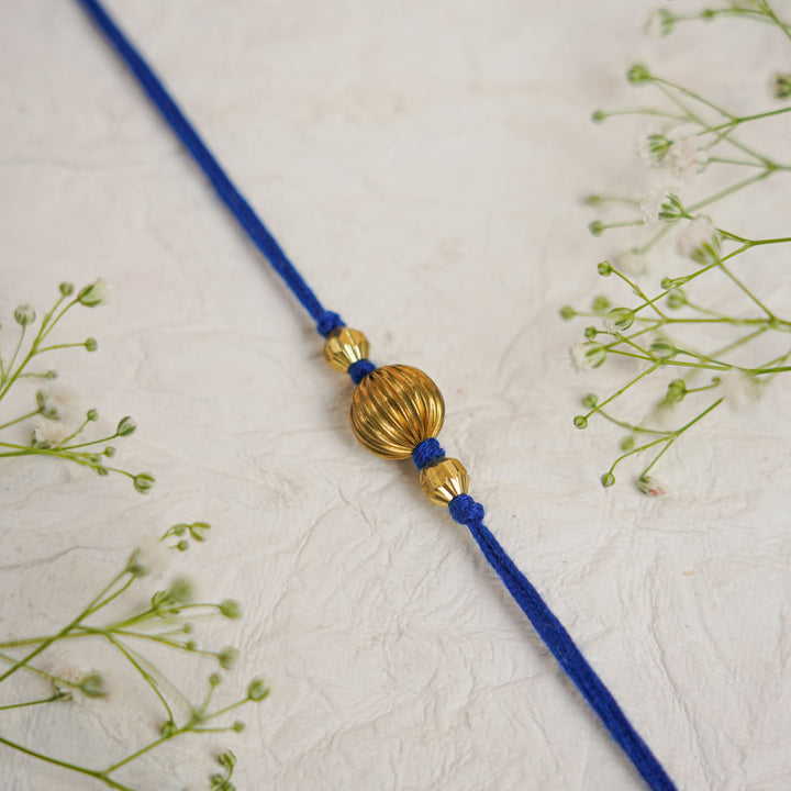 Handmade Swarn Pearl And Ghungroo Rakhi With Roli Chawal - Close-up of blue thread detail
