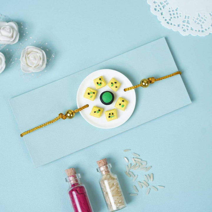 Handmade Miniature Clay Dhokla Rakhi With Roli Chawal - Rakhi on envelope with props