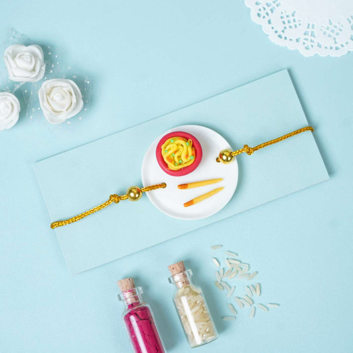 Handmade Miniature Clay Noodles Rakhi With Roli Chawal - Flat Lay with Rakhi and Accessories