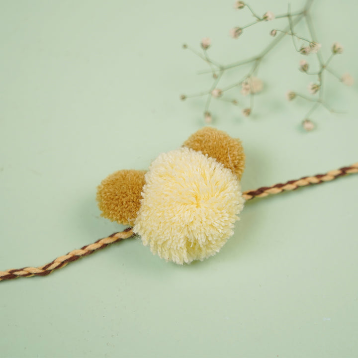 Handmade Pom Pom Teddy Design Kids Rakhi With Roli Chawal - Close-up on Yellow Pom-Pom Bracelet