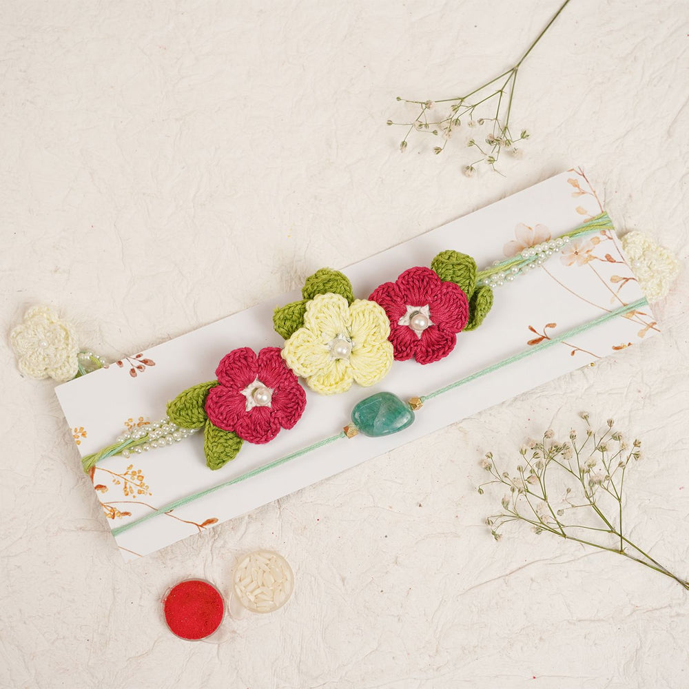 Handmade Reusable Red Floral Bliss Pearl Bhaiya Bhabhi Rakhi With Roli Chawal - Flat lay with decorative elements