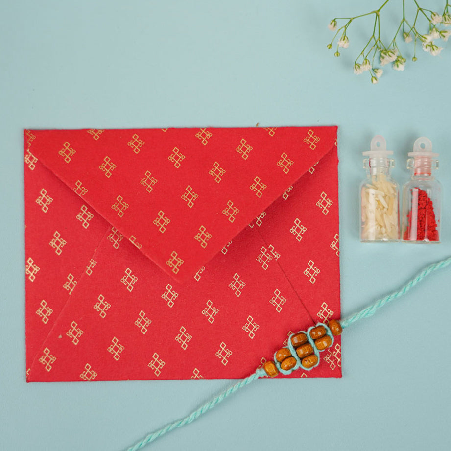 Handmade Beaded Minimalist Rakhi With Roli Chawal - Flat lay with envelope and accessories