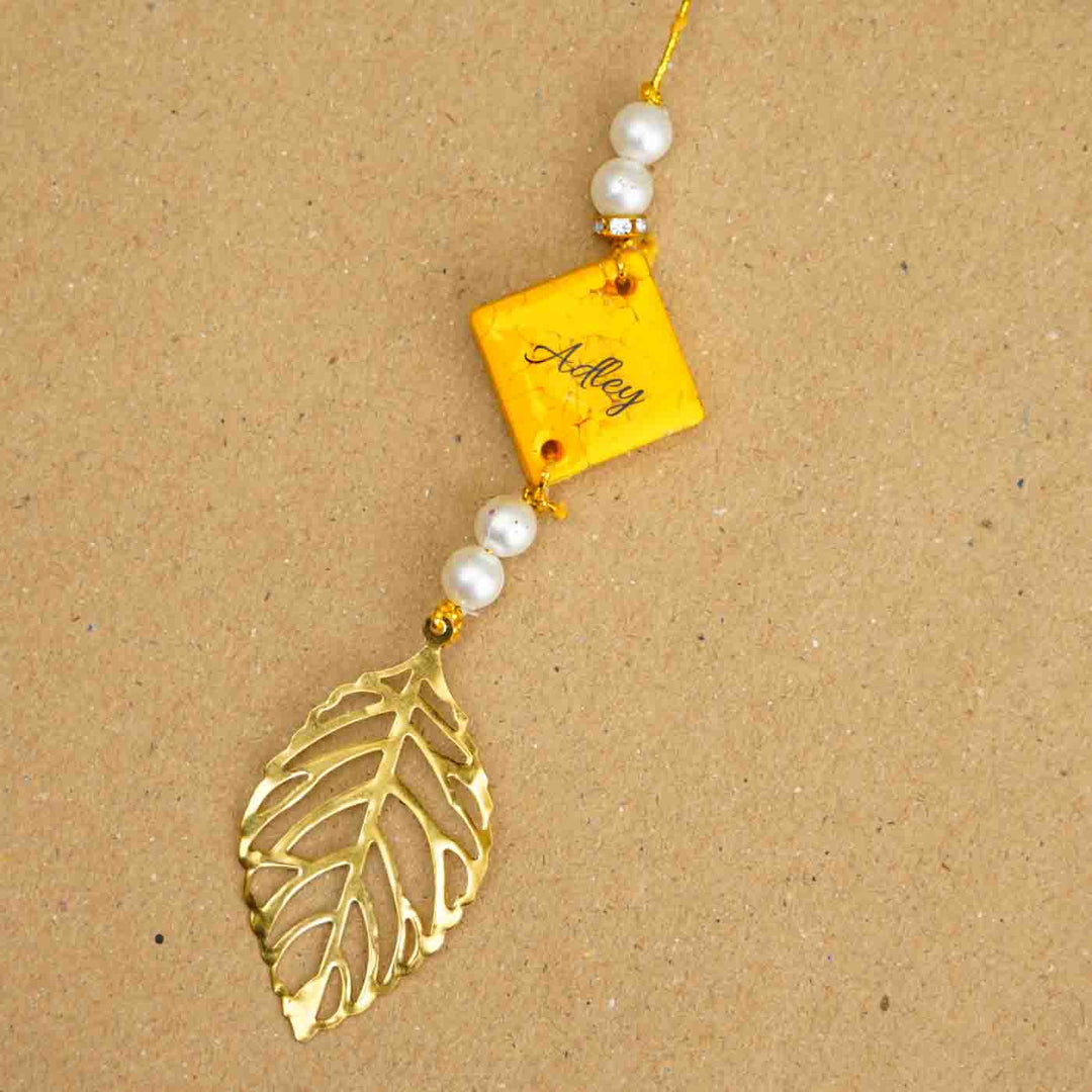 Personalized Handmade Yello Resin Lumba Rakhi For Bhabhi With Roli Chawal - Close-up of personalized rakhi