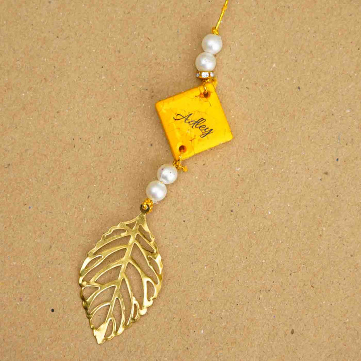 Personalized Handmade Yello Resin Lumba Rakhi For Bhabhi With Roli Chawal - Close-up of personalized rakhi