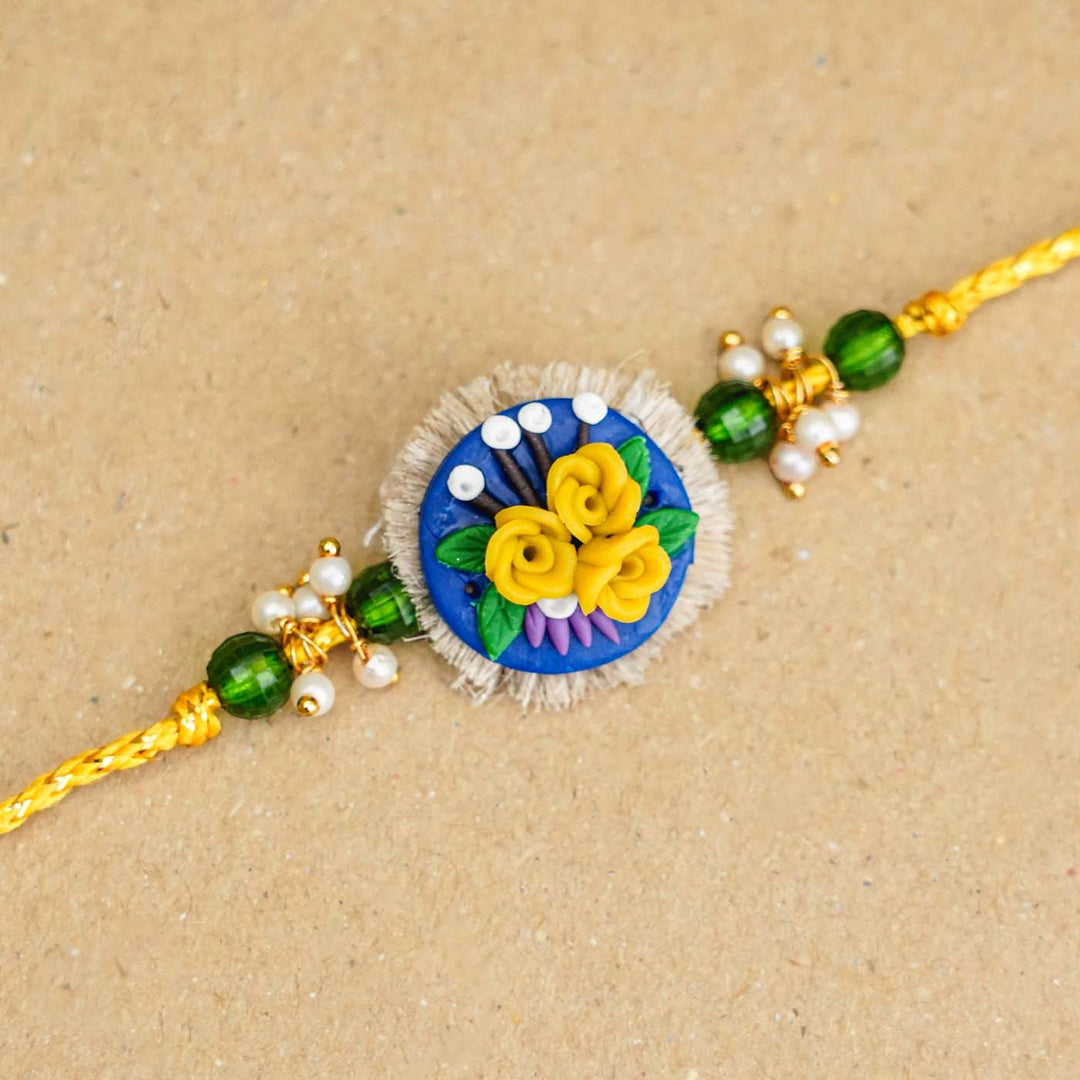 Handmade Miniature Clay Yellow and Blue Floral Rakhi With Roli Chawal