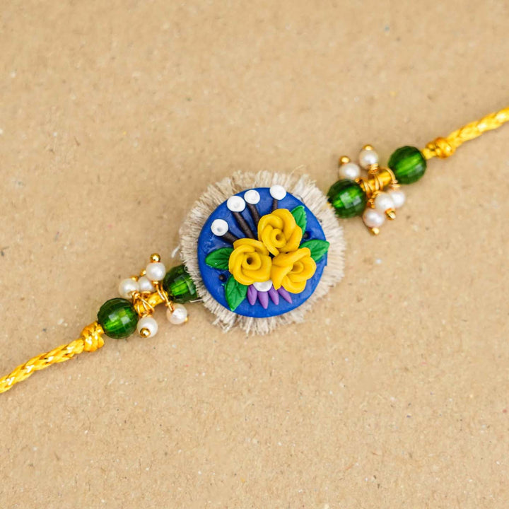 Handmade Miniature Clay Yellow and Blue Floral Rakhi With Roli Chawal