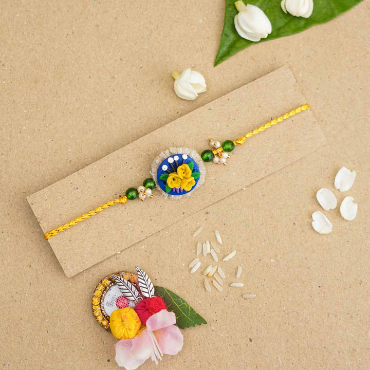 Handmade Miniature Clay Yellow and Blue Floral Rakhi With Roli Chawal