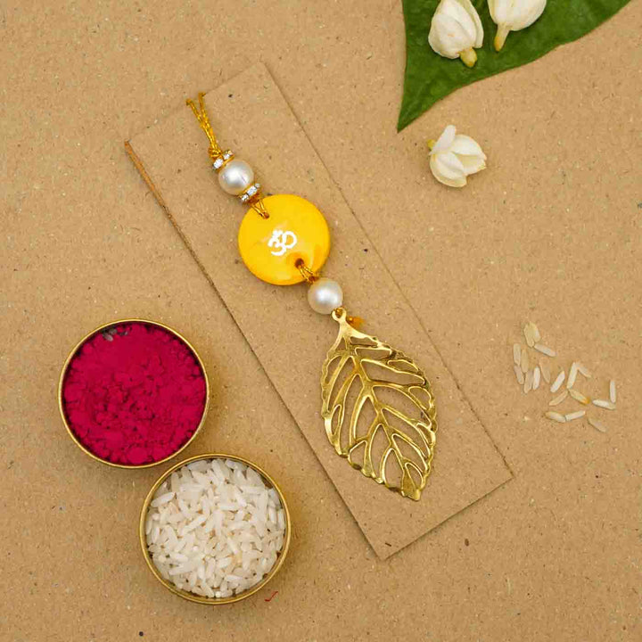 Personalized Handmade Yello Resin Lumba Rakhi For Bhabhi With Roli Chawal - Flatlay with traditional ingredients