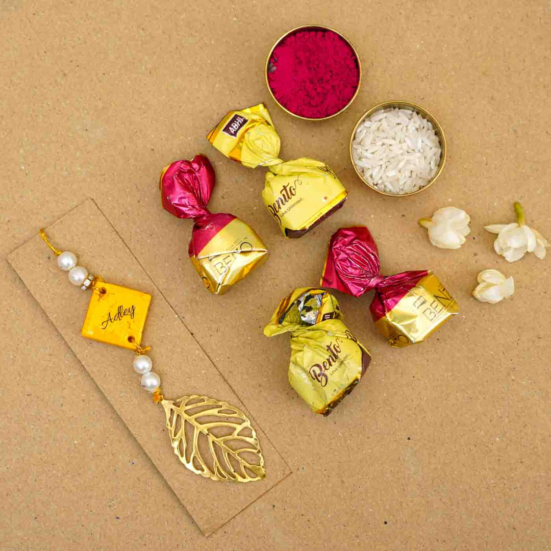 Personalized Handmade Yello Resin Lumba Rakhi For Bhabhi With Roli Chawal - Flatlay personalized rakhi with chocolates