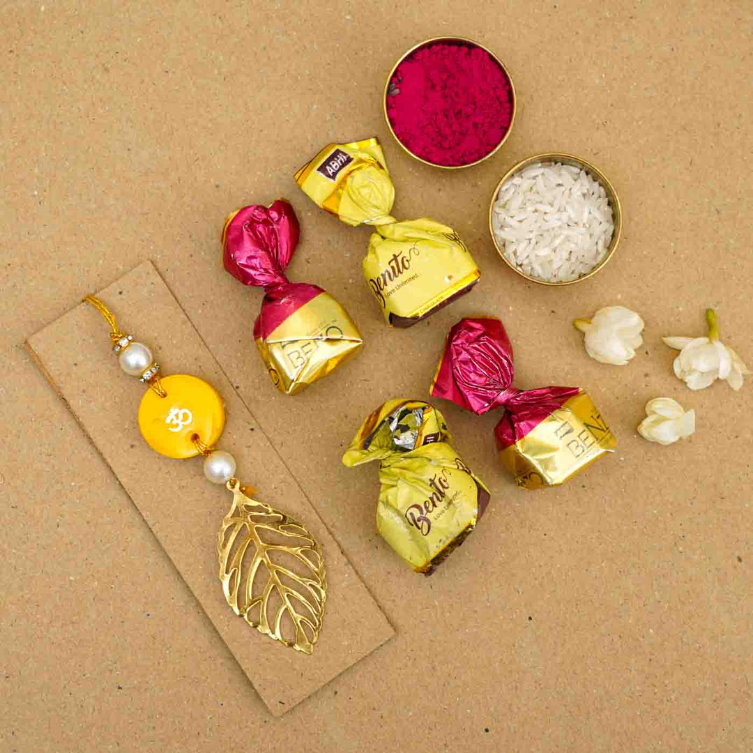 Personalized Handmade Yello Resin Lumba Rakhi For Bhabhi With Roli Chawal - Flatlay with chocolates and flowers