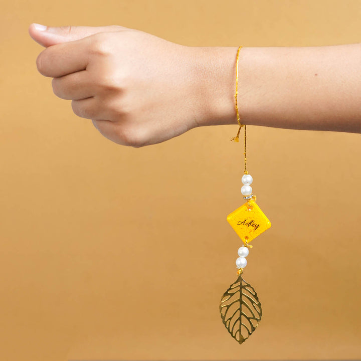 Personalized Handmade Yello Resin Lumba Rakhi For Bhabhi With Roli Chawal - Model wrist with personalized rakhi