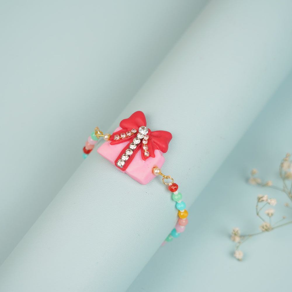Handmade Beaded Gift Box Theme Clay Bracelet Rakhi With Roli Chawal For Sisters - Side View on Cylindrical Holder