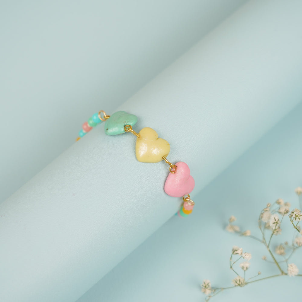 Handmade Beaded Multicolour Hearts Clay Bracelet Rakhi With Roli Chawal For Sisters - Bracelet wrapped on display tube
