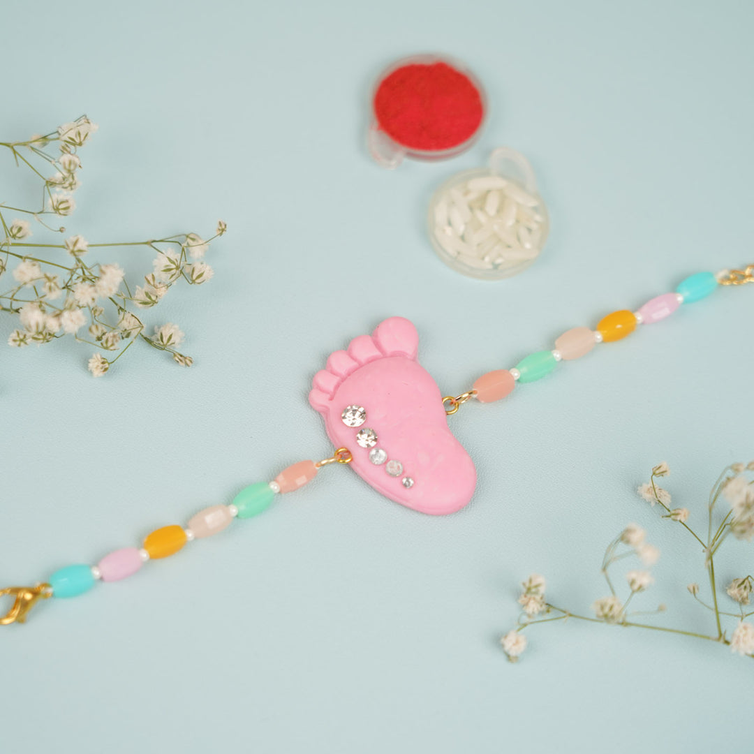 Handmade Blue And Pink Baby Feet Clay Bhaiya Bhabhi Rakhi With Roli Chawal Set Of 2 - Flat Lay with Accessories (4)