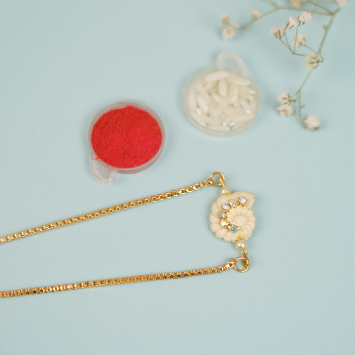 Handmade Golden Shell Clay Bracelet Rakhi With Roli Chawal For Sisters - Flat Lay with Decorative Props