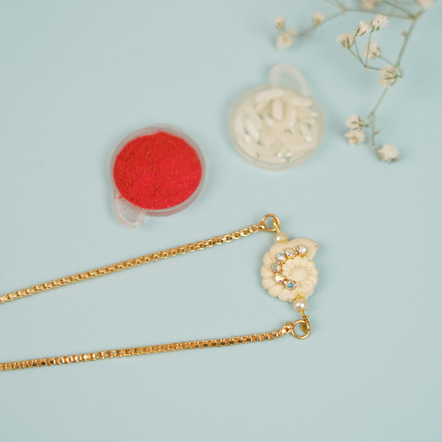 Handmade Golden Shell Clay Bracelet Rakhi With Roli Chawal For Sisters - Flat Lay with Decorative Props