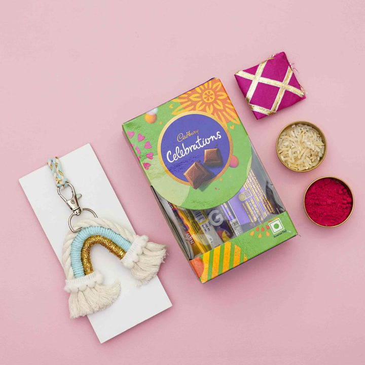 Handmade Macrame Rainbow Theme Cotton Kids Rakhi For Girls With Chocolates And Roli Chawal - Styled flat lay with gift box