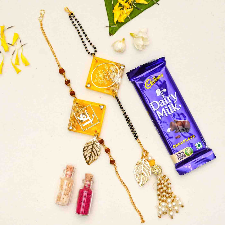 Handmade Resin Sunset Yellow Bhaiya Bhabhi Rakhi With Chocolates And Roli Chawal Set Of 2 - Styled with chocolate and accessories