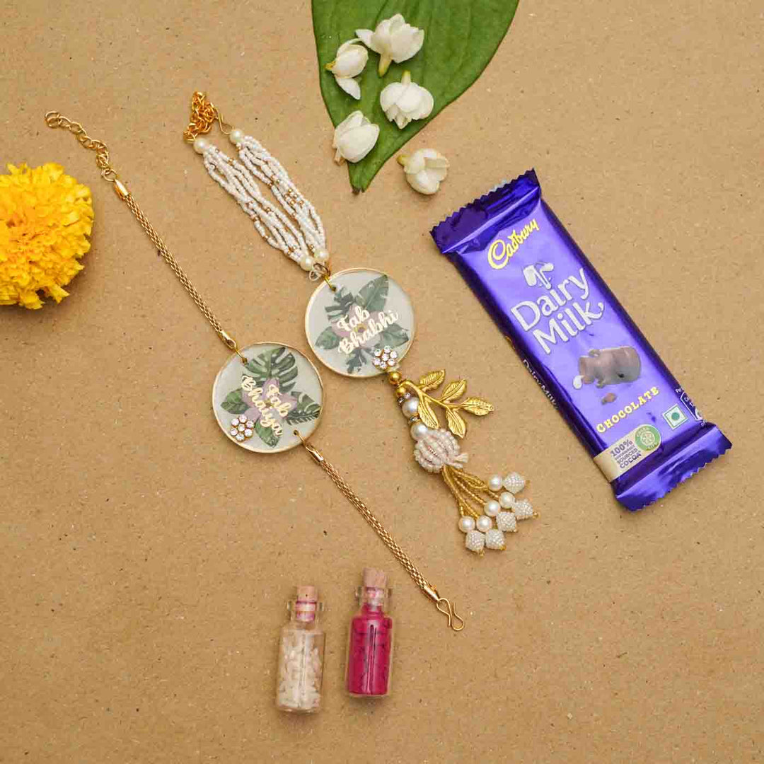 Handmade Resin Fab Bhaiya And Fab Bhabhi Flower Print Rakhi With Chocolates And Roli Chawal Set Of 2 - Bracelets with decorative items beside