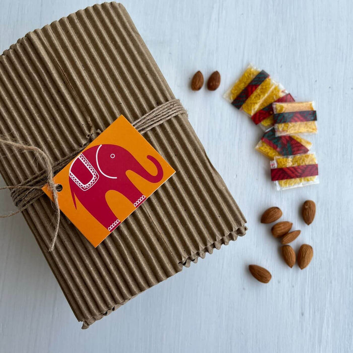 Handcrafted Folk Art Rakhi Hamper For Kids With Rice Roli Haldi 2 - Gift packaging with almonds and chili powder