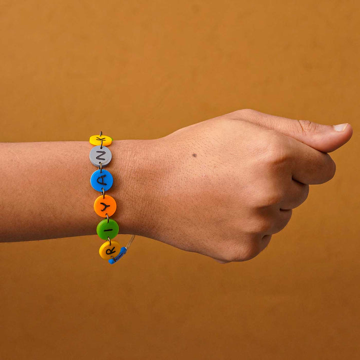 Personalized Handmade Gems Acrylic Rakhi With Roli Chawal - Wrist view with name bead bracelet