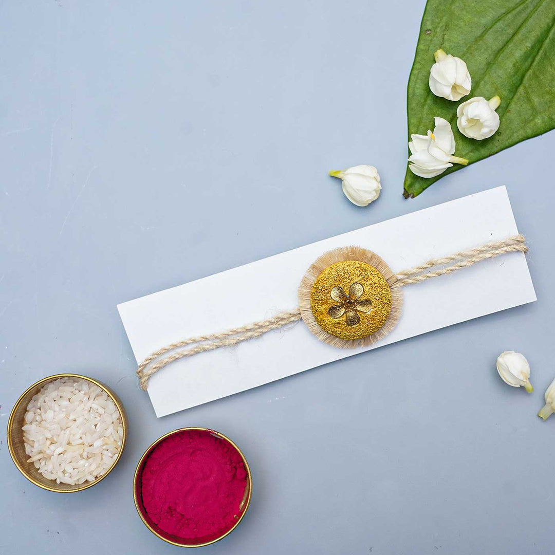 Handmade Papier Mache Gold Floral Rakhi With Roli Chawal - Styled on Packaging with Ritual Items