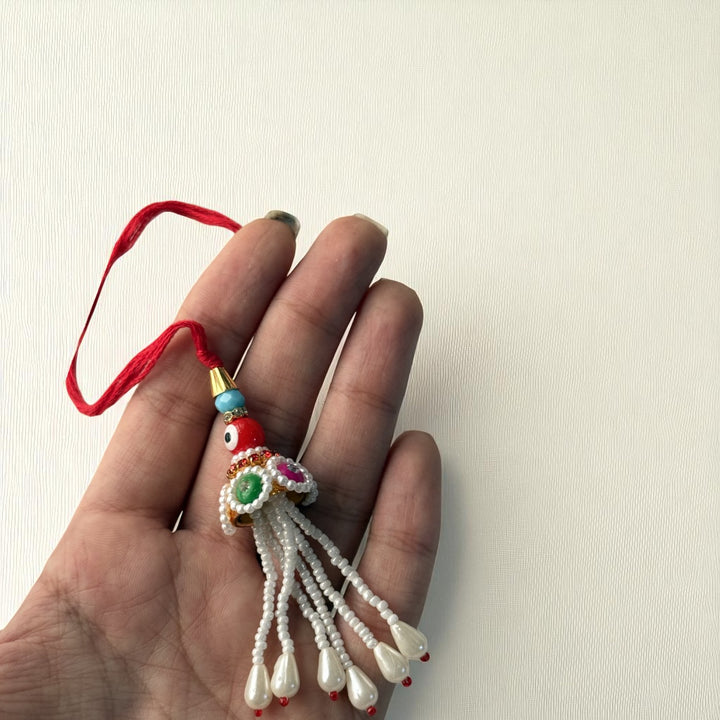 Handmade Red Evil Eye Lumba Rakhi For Bhabhi With Roli Chawal - Single Item Held Close-up