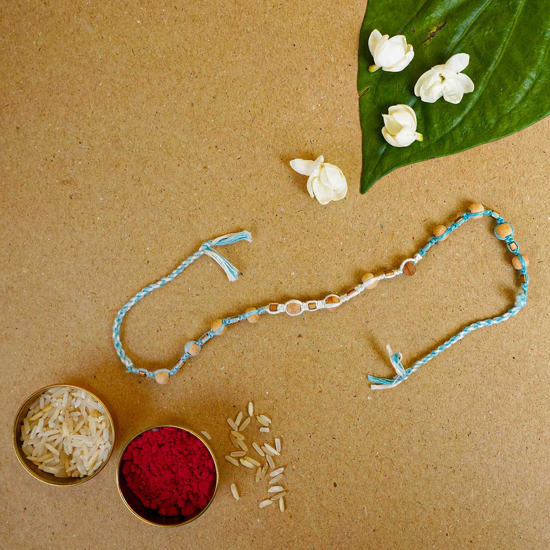 Reusable Beaded Blue Wooden Bead Rakhi With Roli Chawal - Laid flat with traditional items