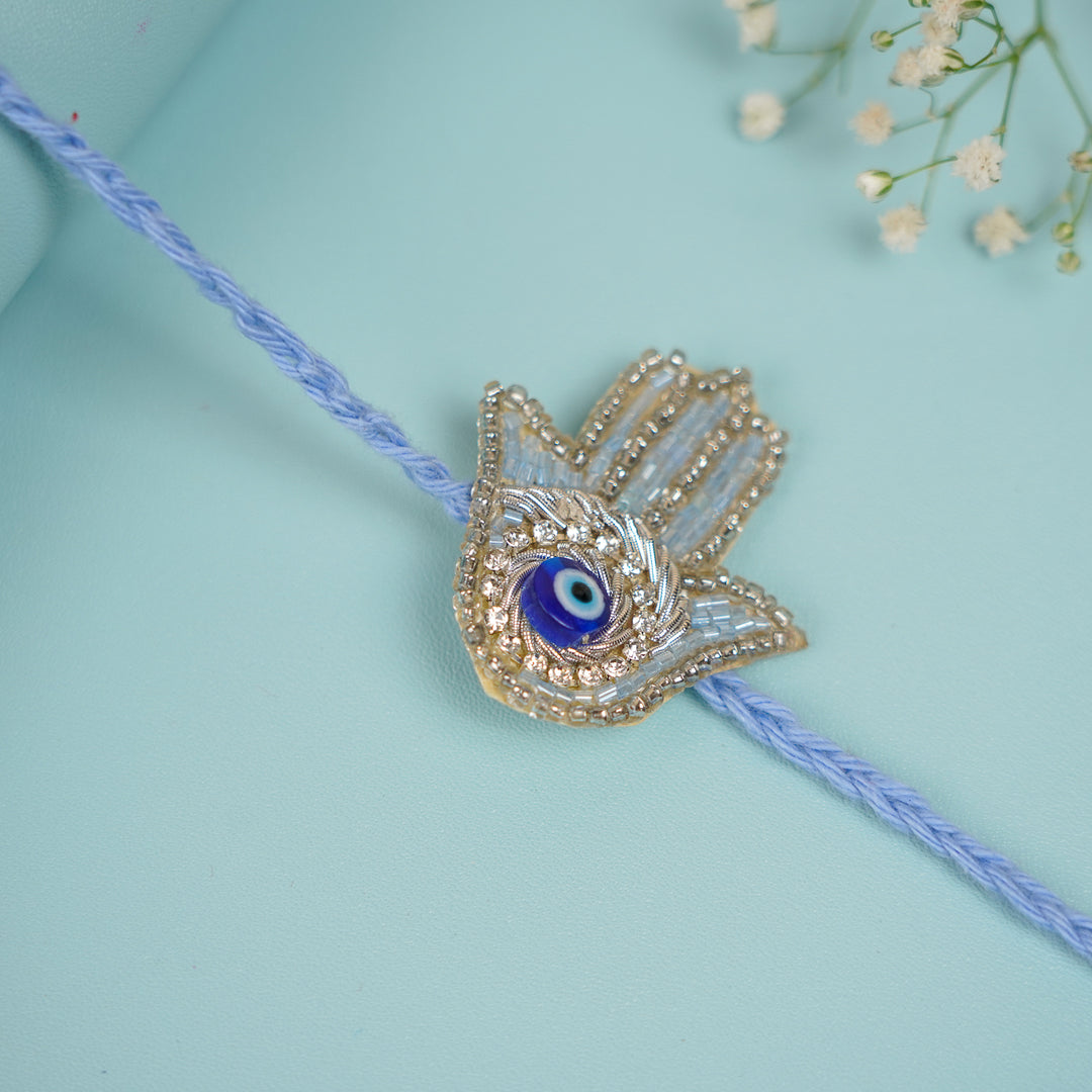 Handmade Beaded Evil Eye Hamsa Hand Rakhi With Roli Chawal - Close-up of Hand Charm