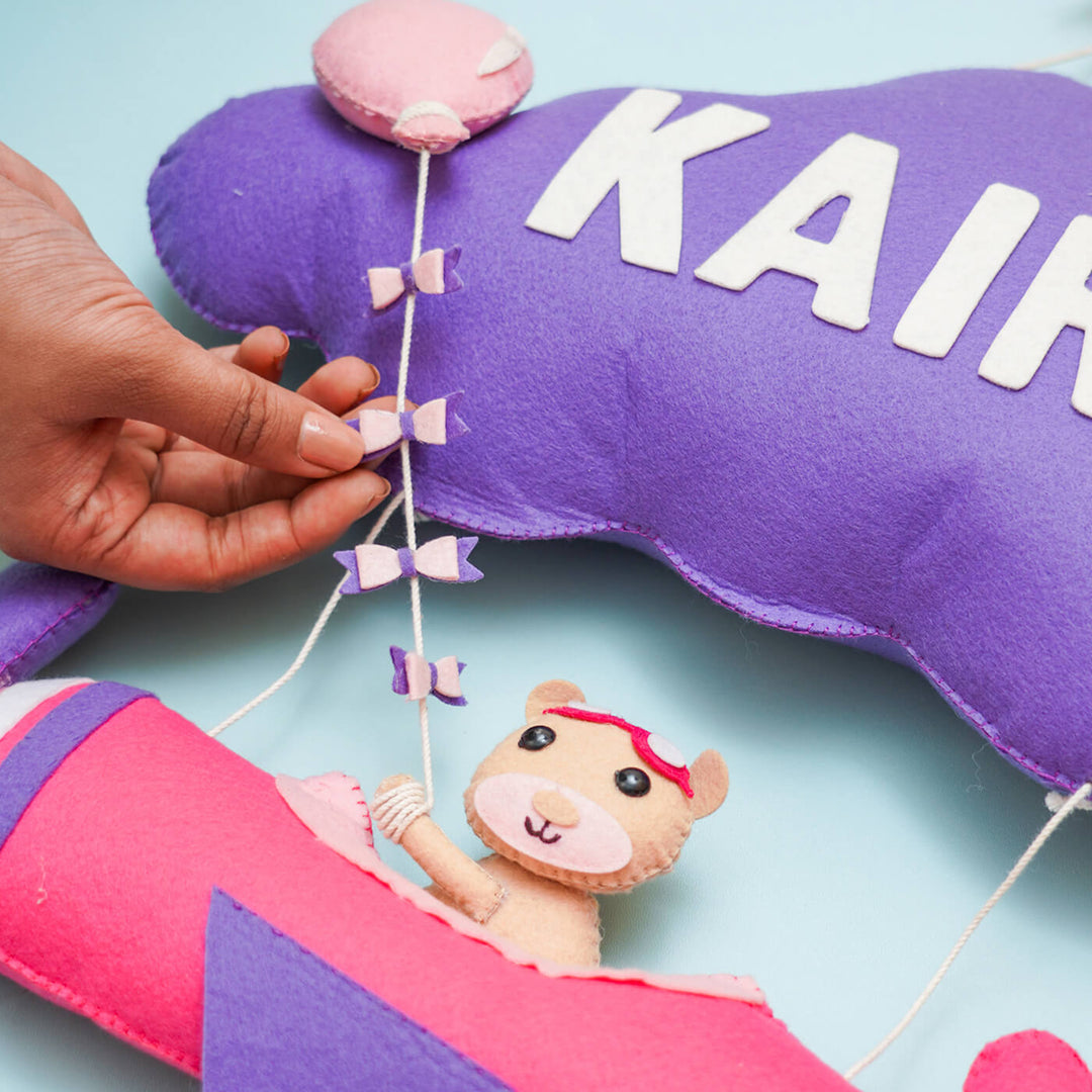 Handmade Personalized Felt Name Hanging Aviator - Close-up of Hand Adjusting Decoration