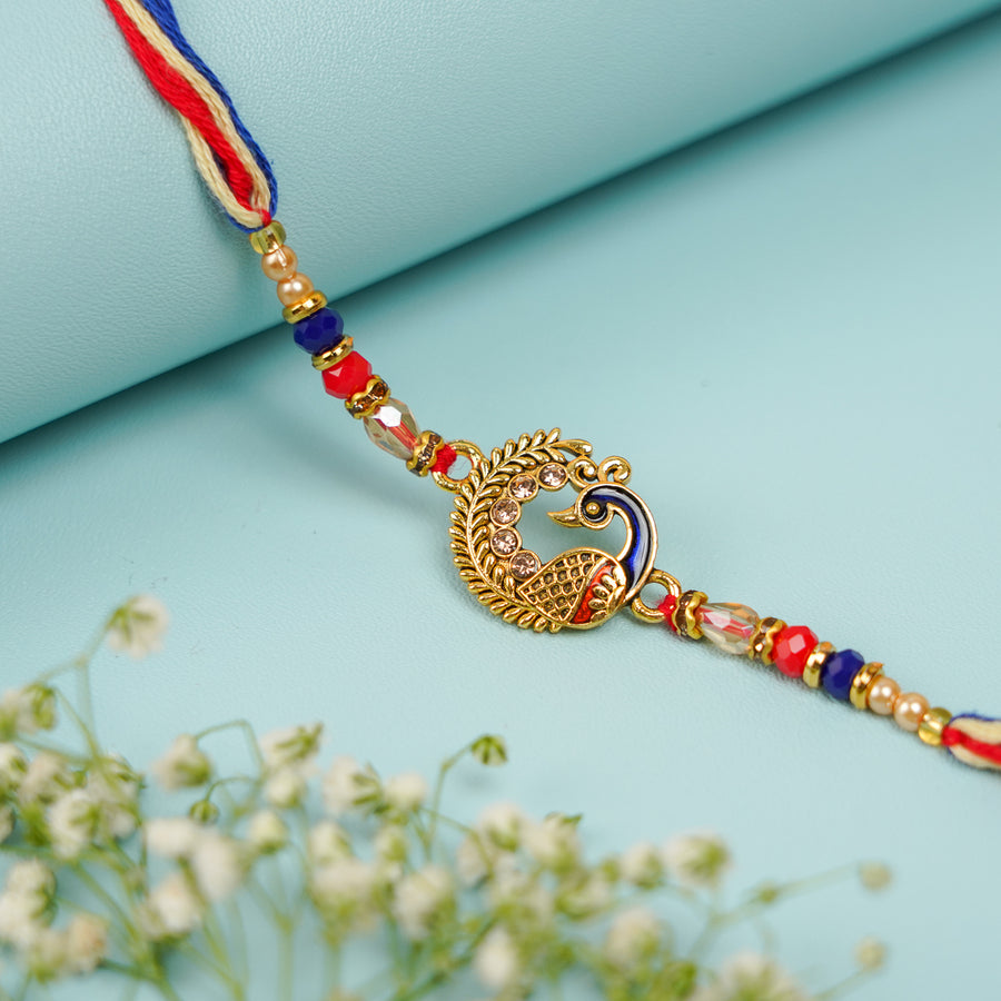 Handmade Blue And Red Peacock Jadtar Rakhi With Roli Chawal - Close-up of central design
