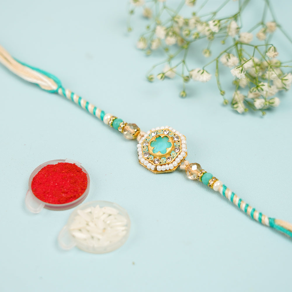 Handmade Sea Green Judtar Rakhi With Roli Chawal - Flat Lay with Accessories and Flowers